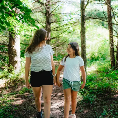 A mother and daughter walk through a wooded trail