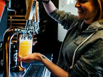 A woman pours a beer from a tap