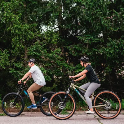 man and woman cycling by a line of trees