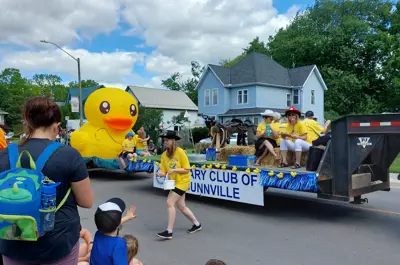 a parade runs through a small town with a large rubber ducky on a float