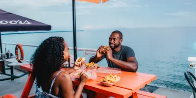 Couple eating lunch on patio by beach