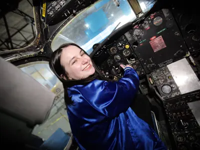 A girl plays with the instruments in an airplane cockpit