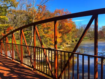 Colourful leaves are the background of a bridge over a creek