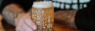 Hand holding a beer on a pub table