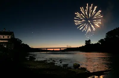 The Old Mill in Caledonia next to the river shown at night with fireworks.