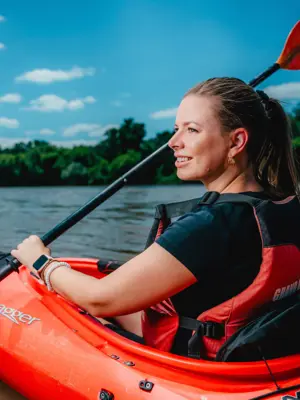 A woman paddles in a red kayak