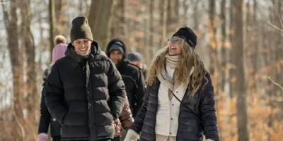 A woman leads a group of people on a walk through a wintery forest