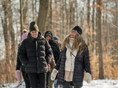 A woman leads a group of people on a walk through a wintery forest