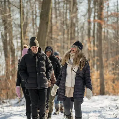 A woman leads a group of people on a walk through a wintery forest