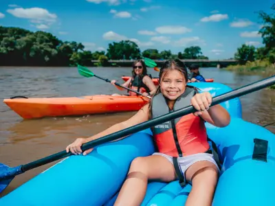 A river with a girl in a raft and other people in kayaks enjoying paddling