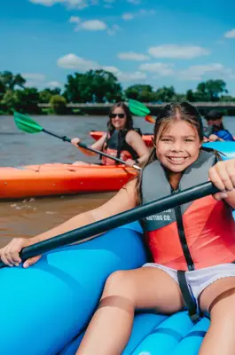 A river with a girl in a raft and other people in kayaks enjoying paddling